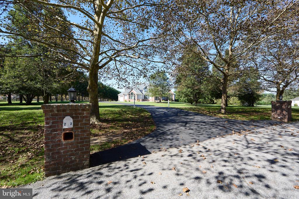 House at the end of a tree-lined driveway with brick pillars and a number 22 plaque.