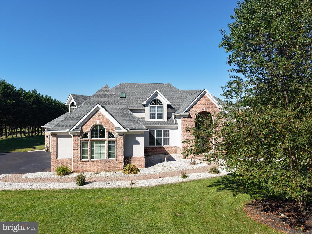Brick-and-siding house with a gray gabled roof, arched windows, and a curved walkway.