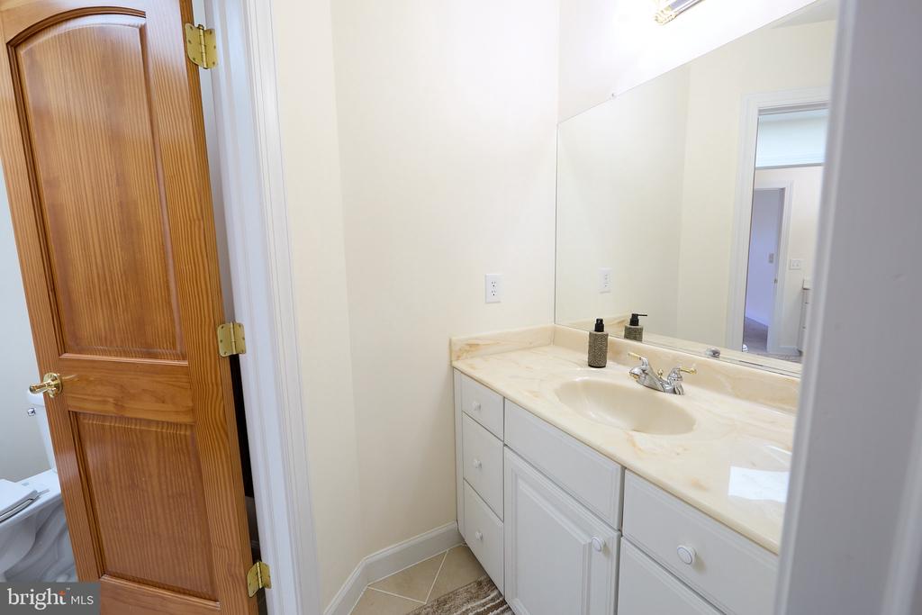 Bathroom vanity with a cream countertop and large mirror beside an open wooden door.