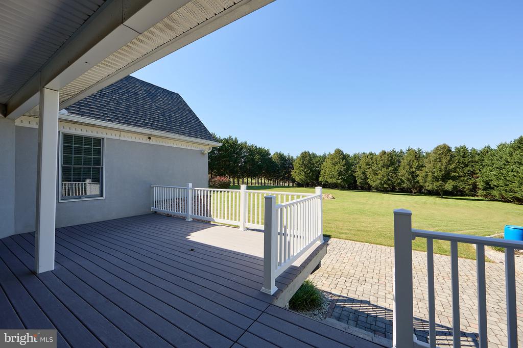 Rear deck with white railings overlooking a spacious lawn and tree line.