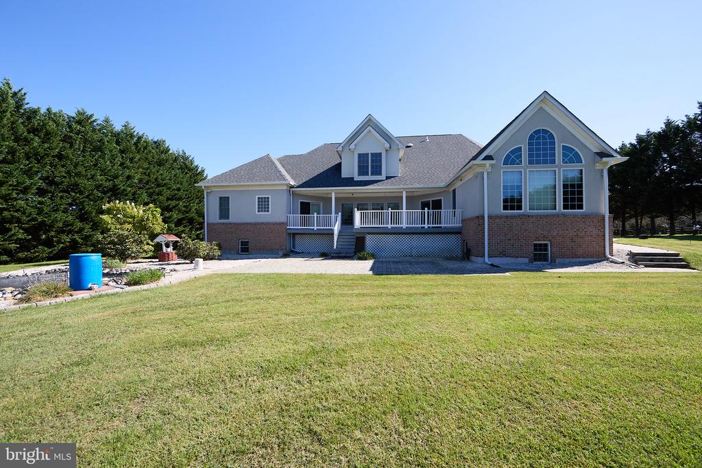 Rear of a two-story house with a raised deck, arched windows, and broad lawn.