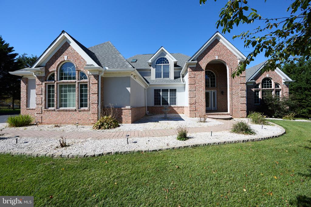Brick-and-stucco home with a curved entry, arched windows, and landscaped front lawn.