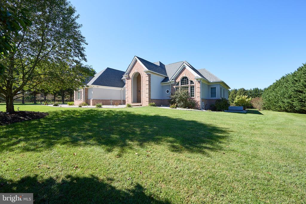 Brick-accented home with a large arched entry, broad lawn, and mature shade tree.