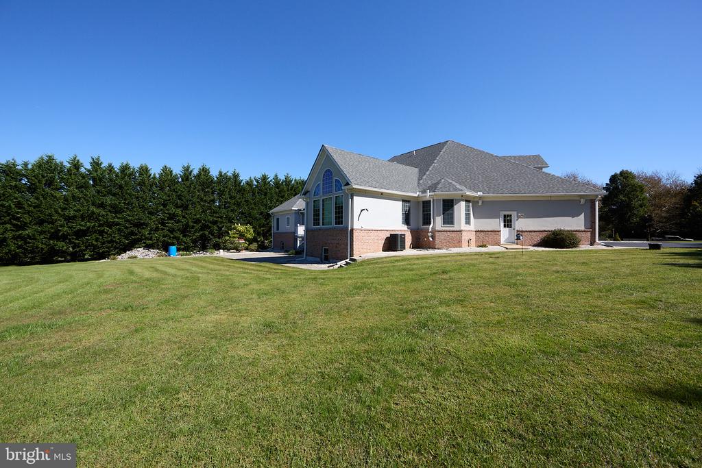 House with a large arched window, brick lower walls, and a broad lawn.