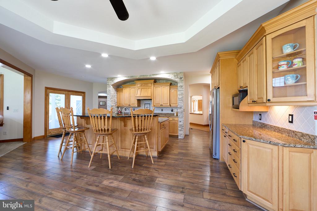 Kitchen with a large wood island, bar stools, granite counters, and stone range wall.