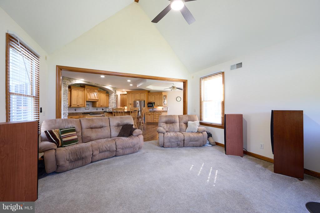 Living room with vaulted ceiling and recliners, opening onto a wood-cabinet kitchen.