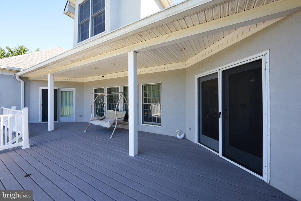 Covered rear deck with gray flooring, white supports, and a hanging bench swing.