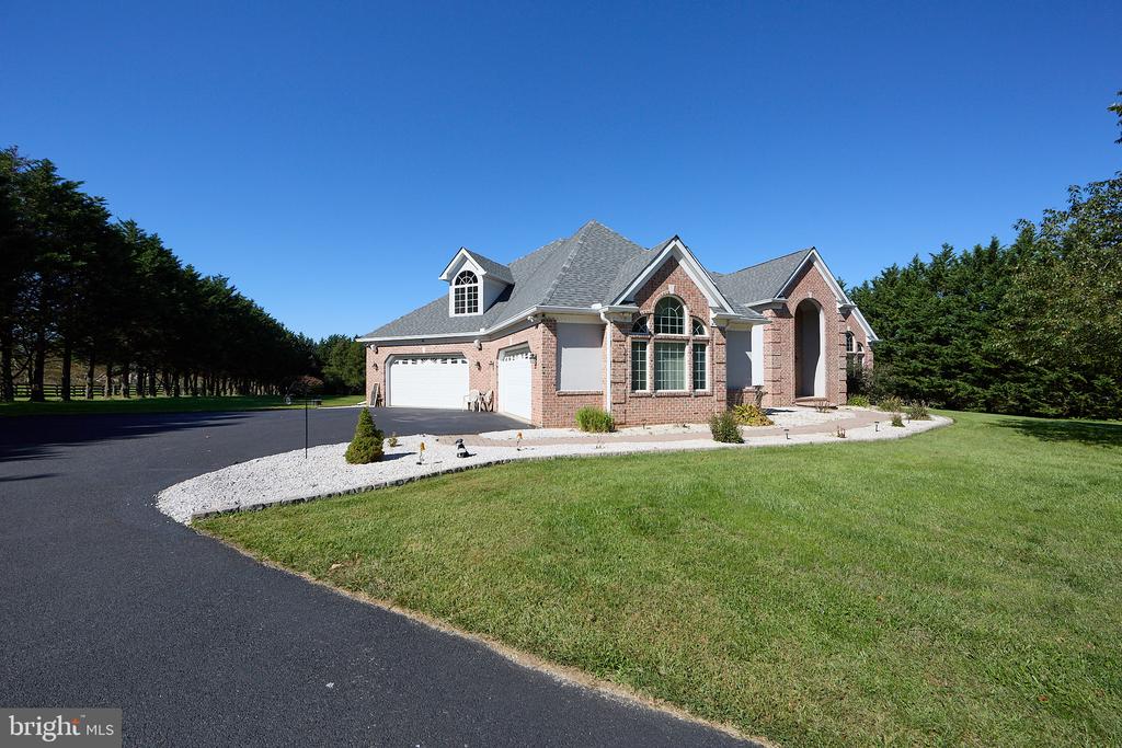 Brick house with a gray gabled roof, arched entry, two-car garage, and curved driveway.