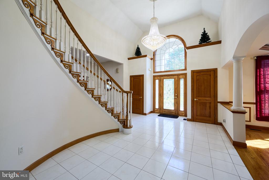 Two-story foyer with a sweeping staircase, crystal chandelier, and arched window above the front door.