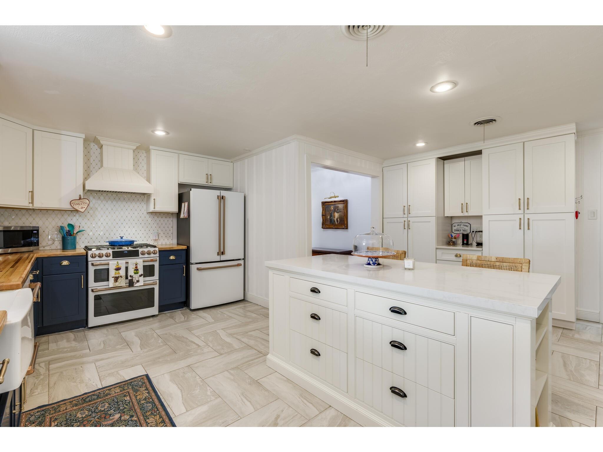 Kitchen with a large white island, navy lower cabinets, and a wide range.