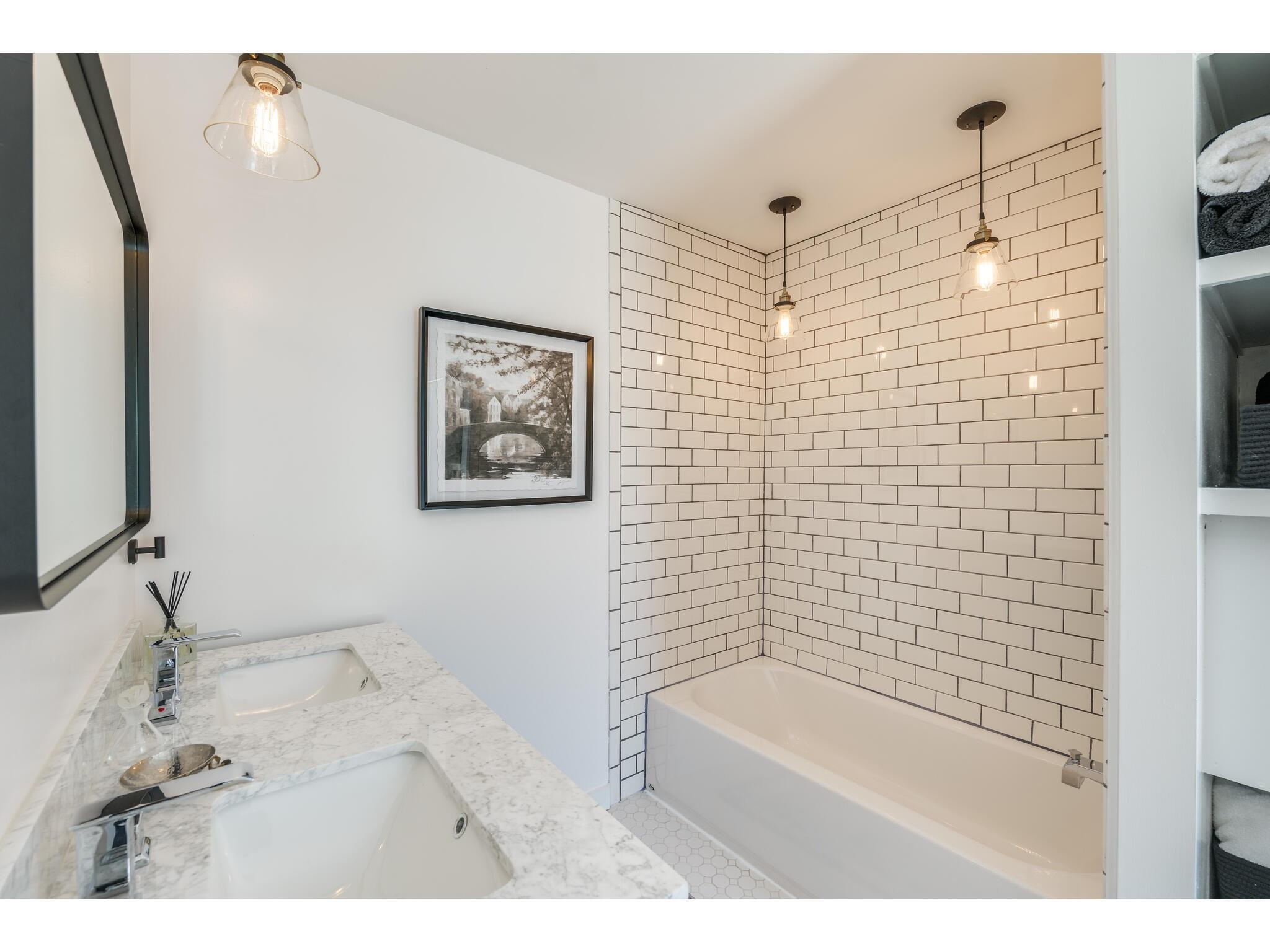 Bathroom with a subway-tile tub surround and double marble-look vanity.