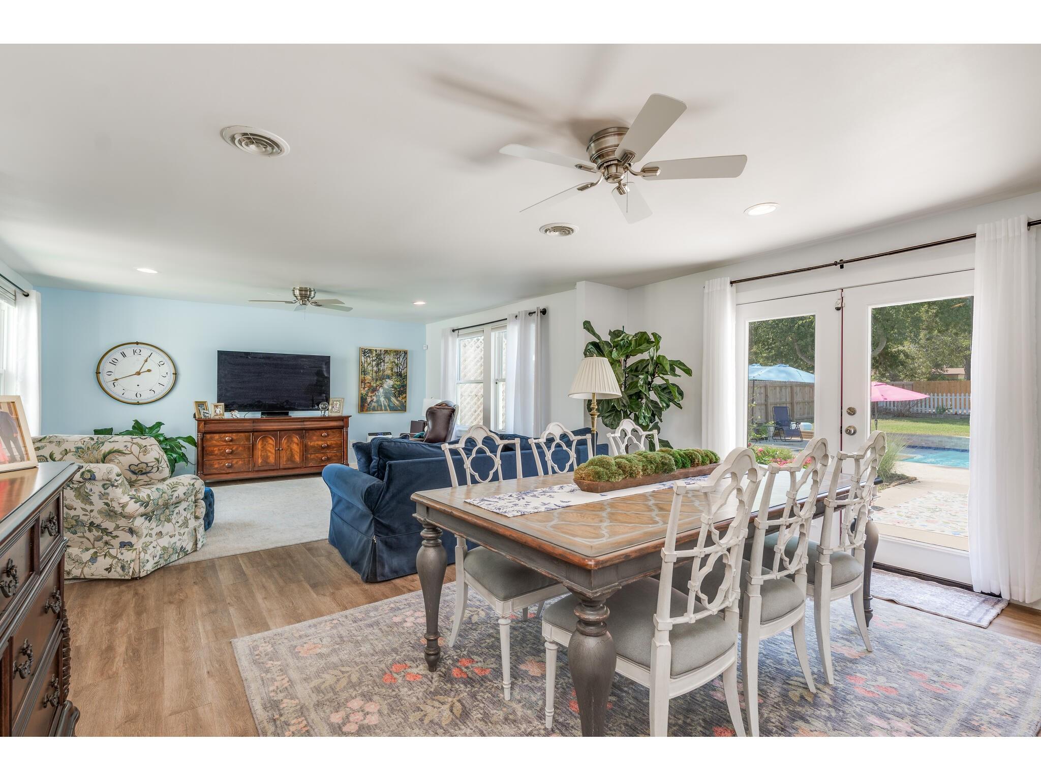 Open-plan living and dining room with French doors overlooking a backyard pool.