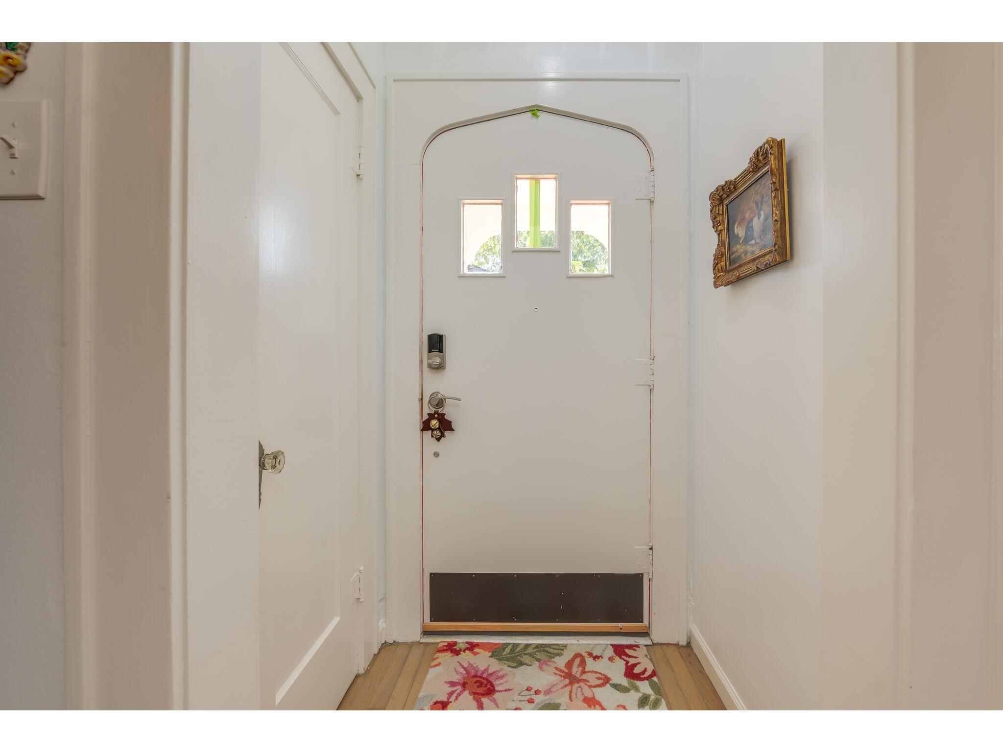Entryway with a white front door, three narrow windows, and a floral rug.