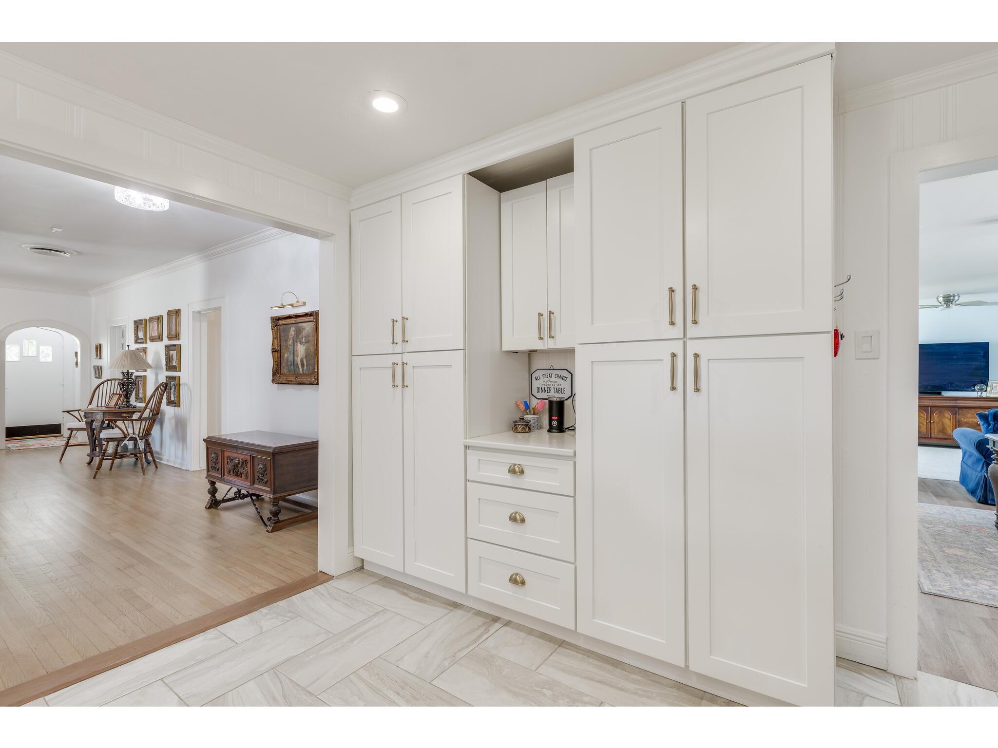 White built-in cabinets with brass pulls and a countertop niche between the dining and living areas.