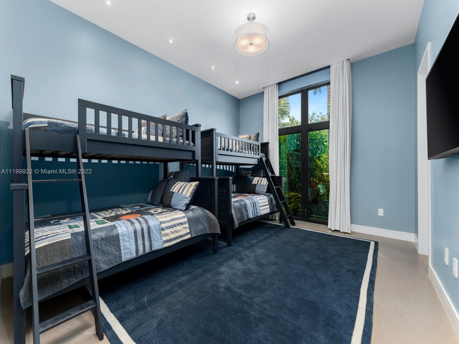 Bedroom with two dark wood bunk beds and a tall window overlooking greenery.