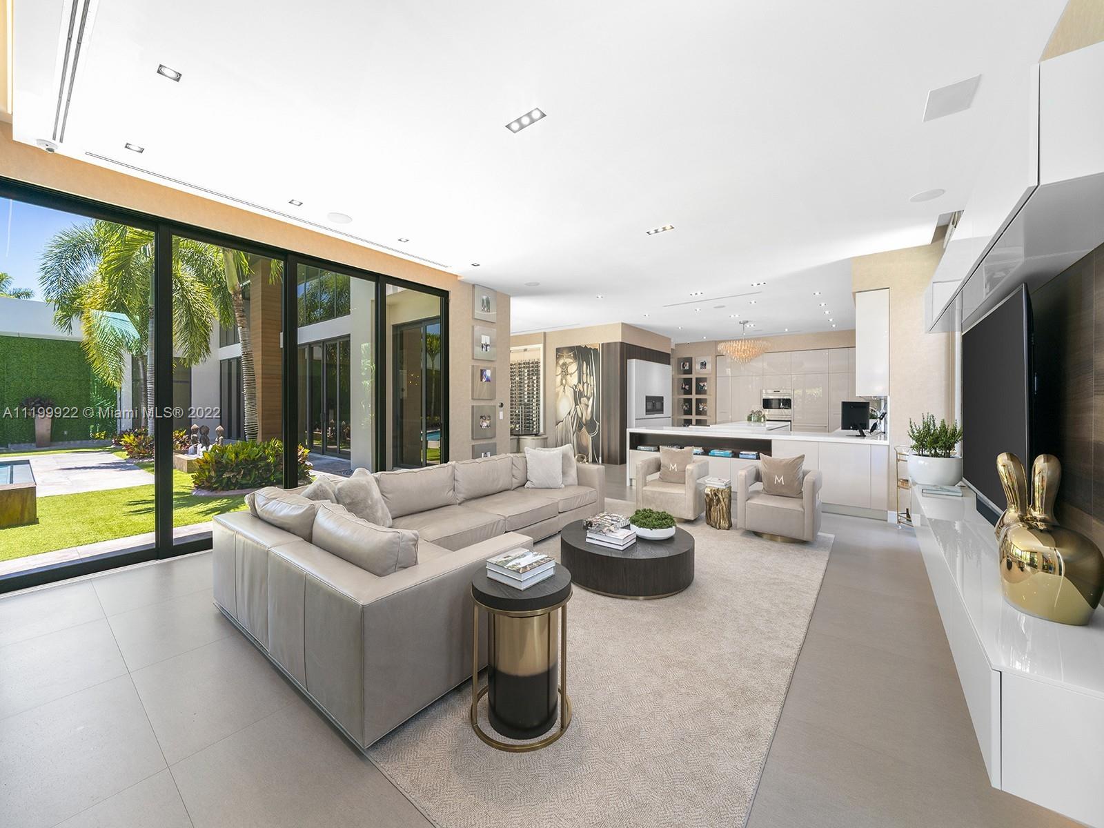 Modern living room with a large sectional and floor-to-ceiling glass doors opening to the garden.