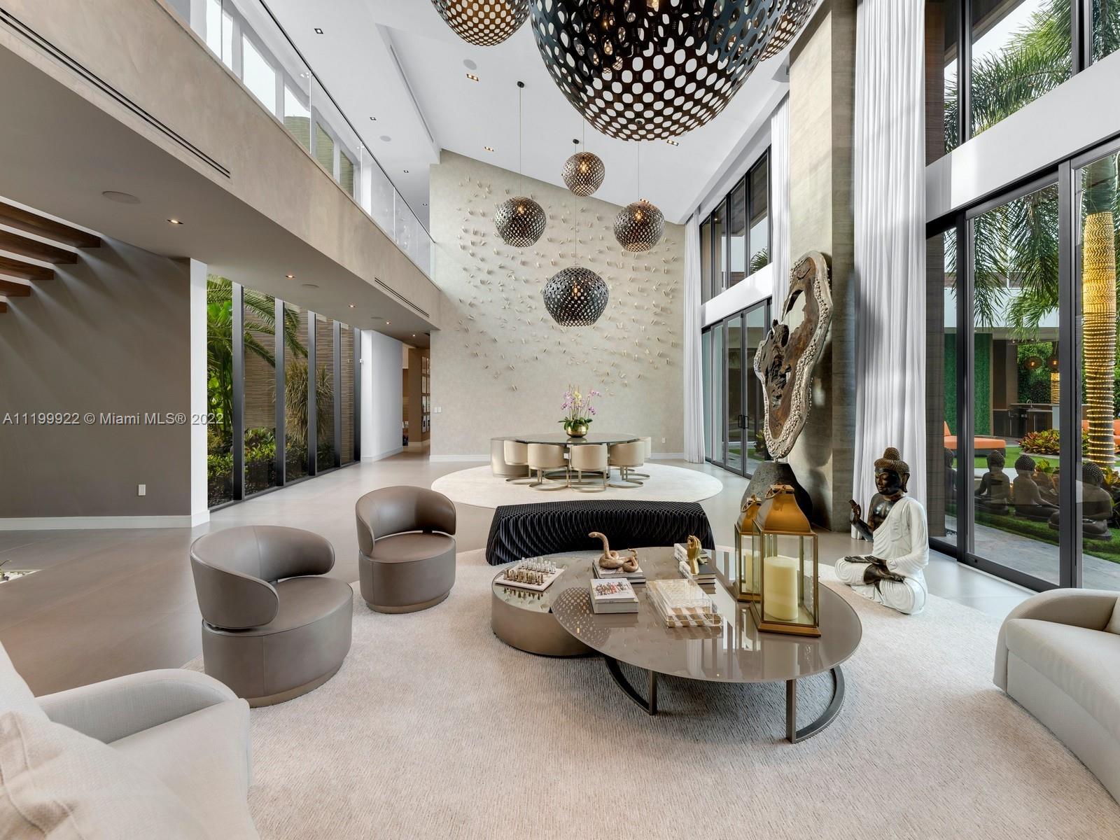 Double-height living room with sculptural pendant lights, modern seating, and floor-to-ceiling garden windows.