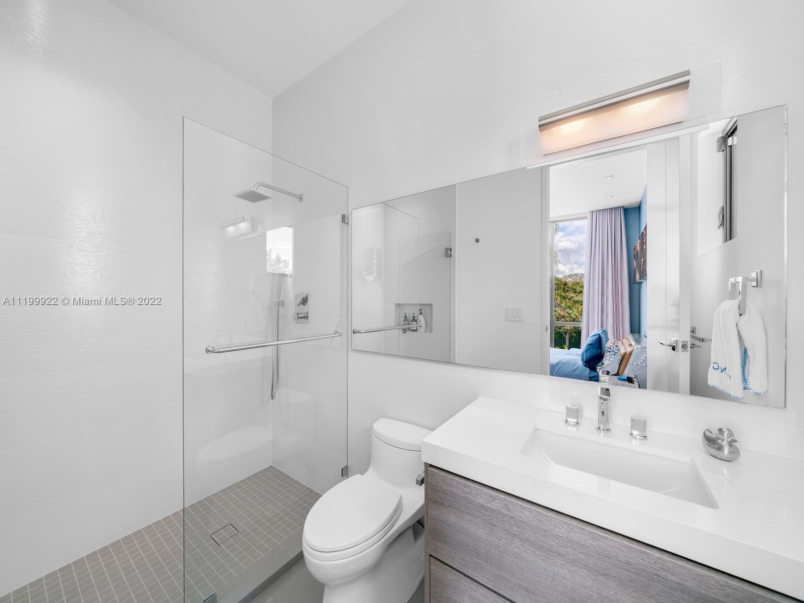 Modern bathroom with a glass walk-in shower, gray tile floor, and wood-finish vanity.