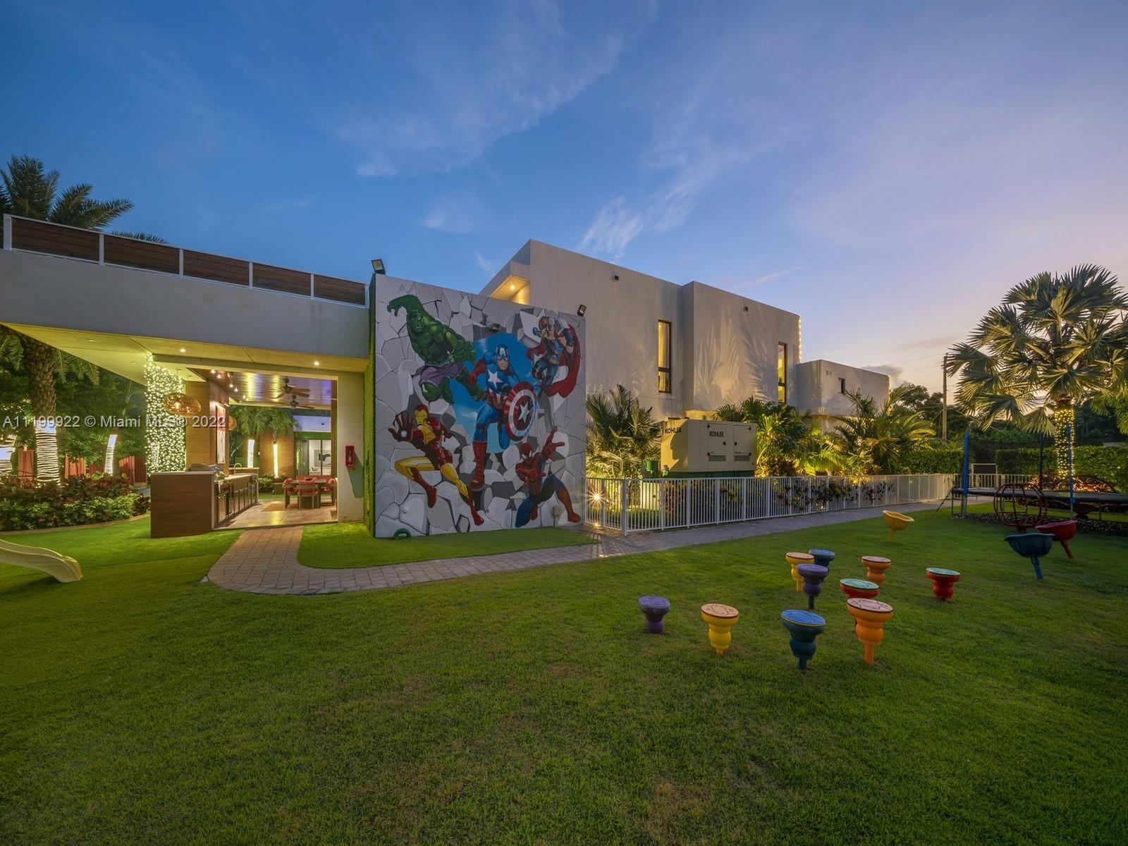 Modern home at dusk with a superhero mural, covered patio, and landscaped play area.