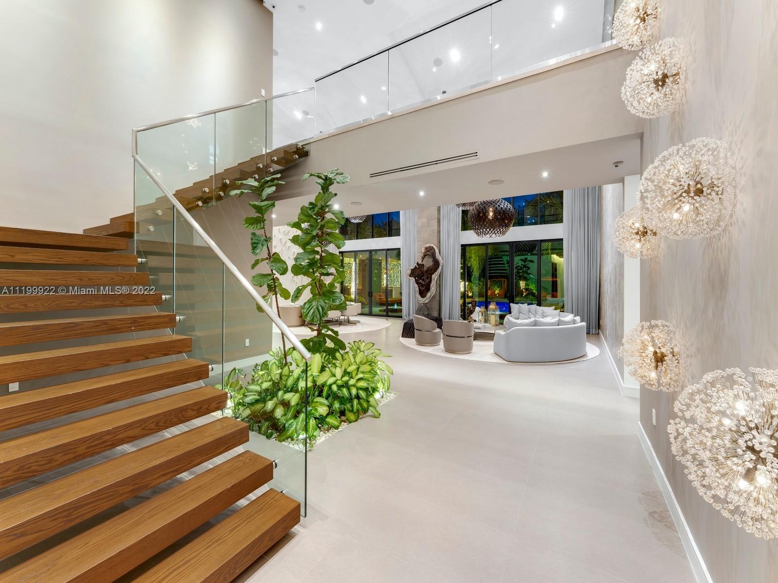 Double-height living room with a floating wood staircase, glass railings, and white seating.