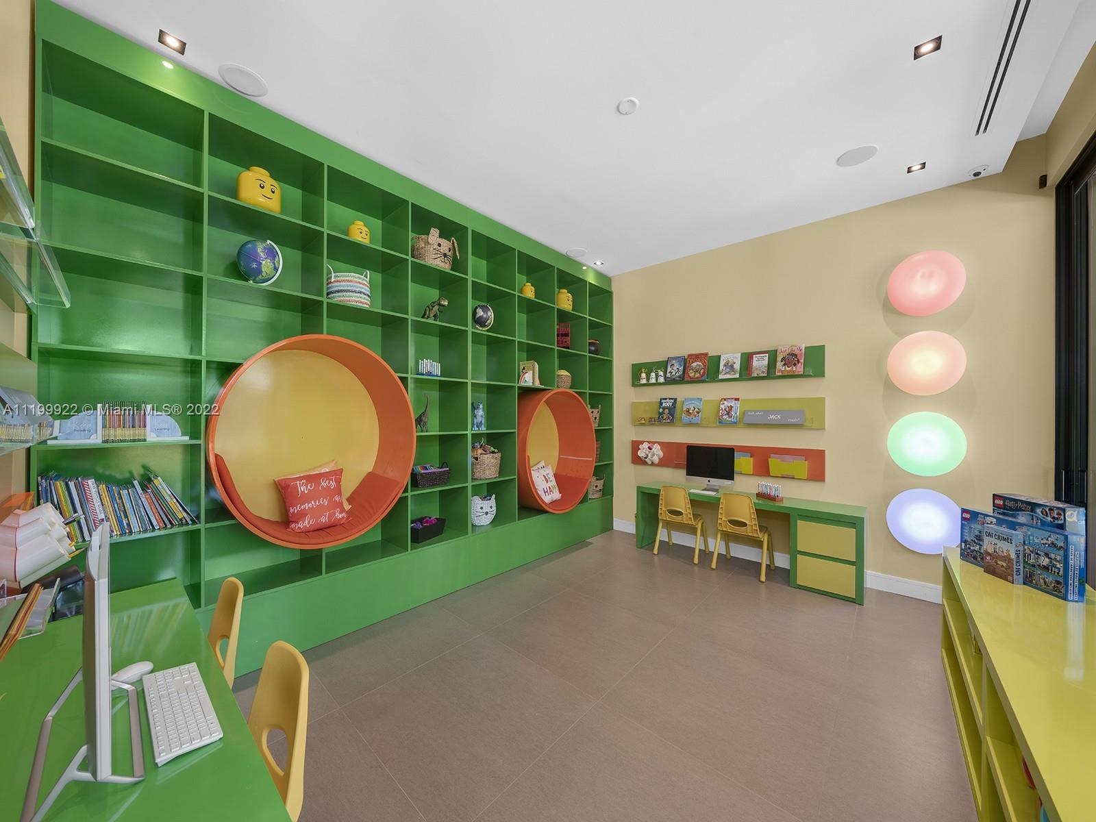 Children’s playroom with green bookcases, orange reading nooks, and a small desk.
