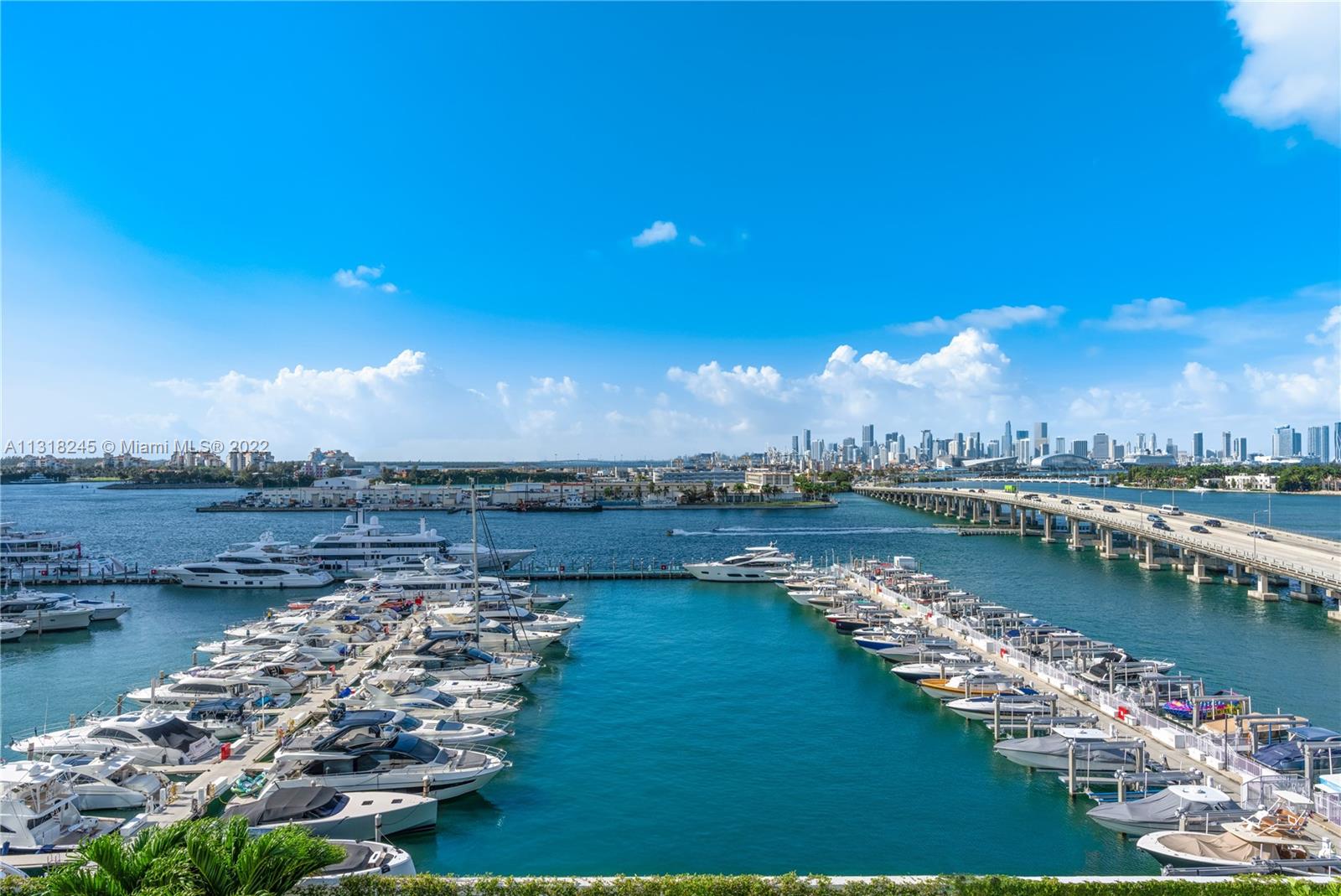 Miami Beach marina with yachts, a bridge, and the downtown skyline across turquoise water.