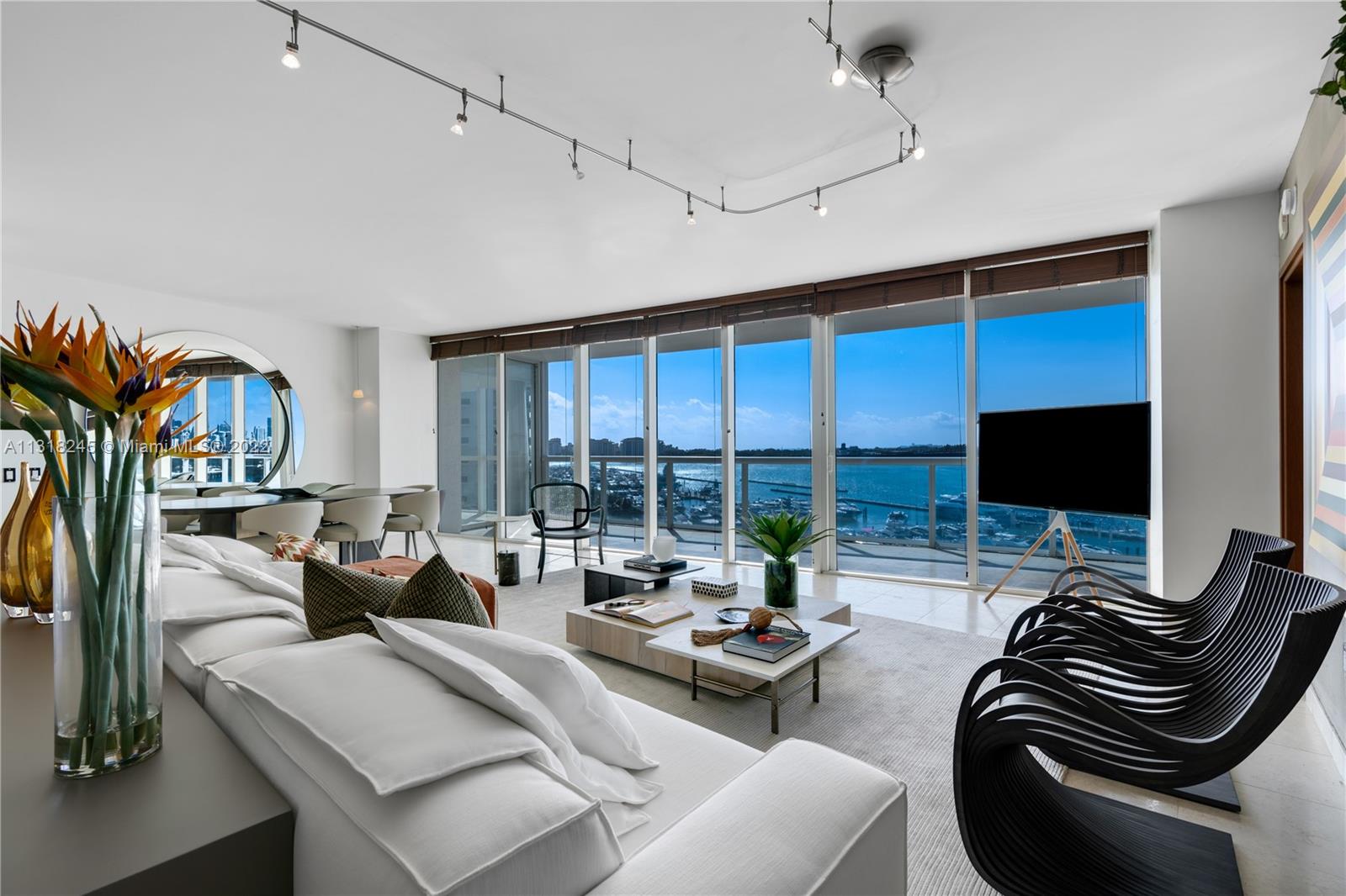 Furnished living room with floor-to-ceiling windows overlooking a marina and water.