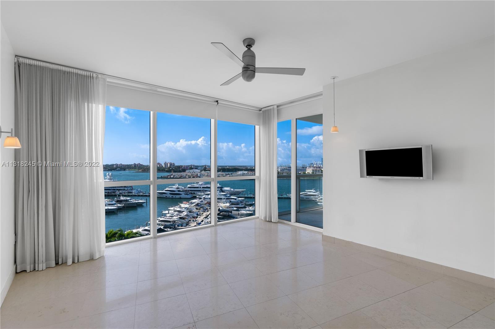 Vacant condo living area with floor-to-ceiling windows overlooking a marina and water.
