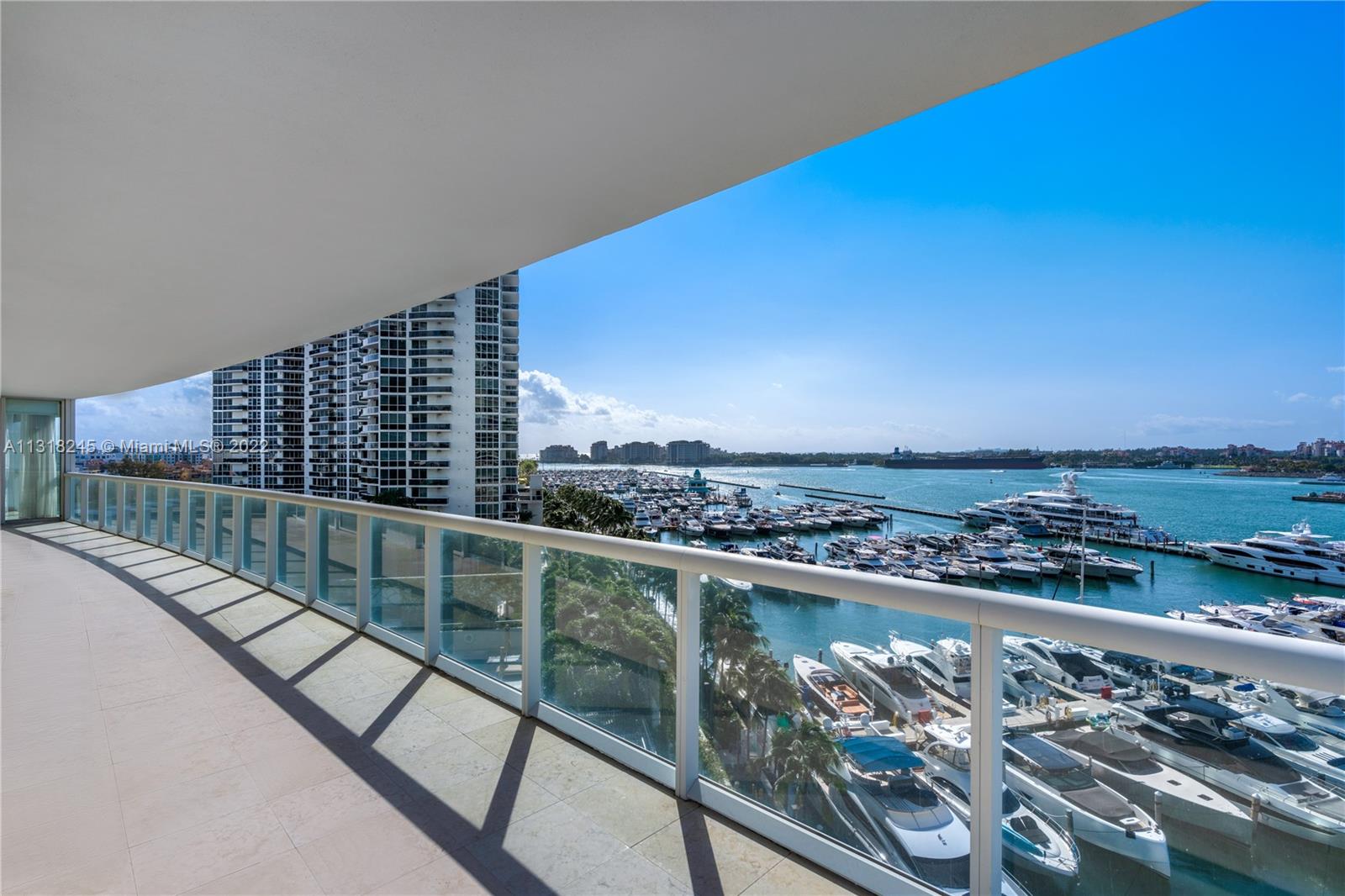High-rise balcony overlooking a marina filled with boats and blue water.