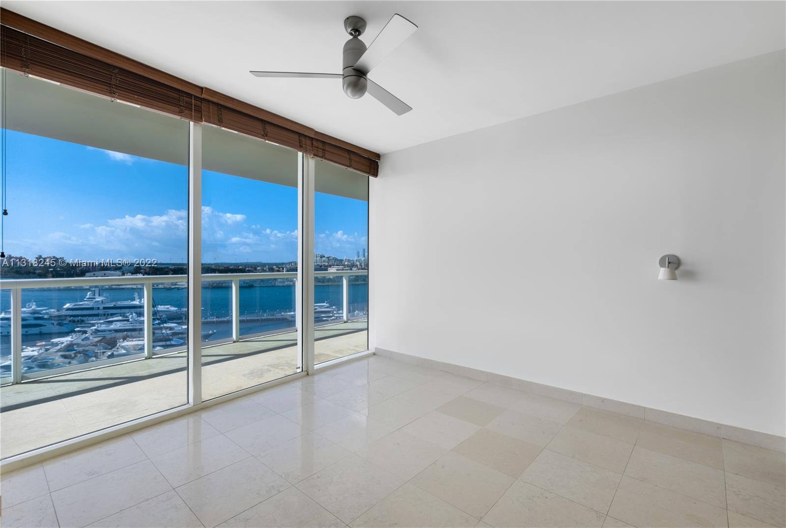 Empty condo interior with floor-to-ceiling windows overlooking a marina and water.