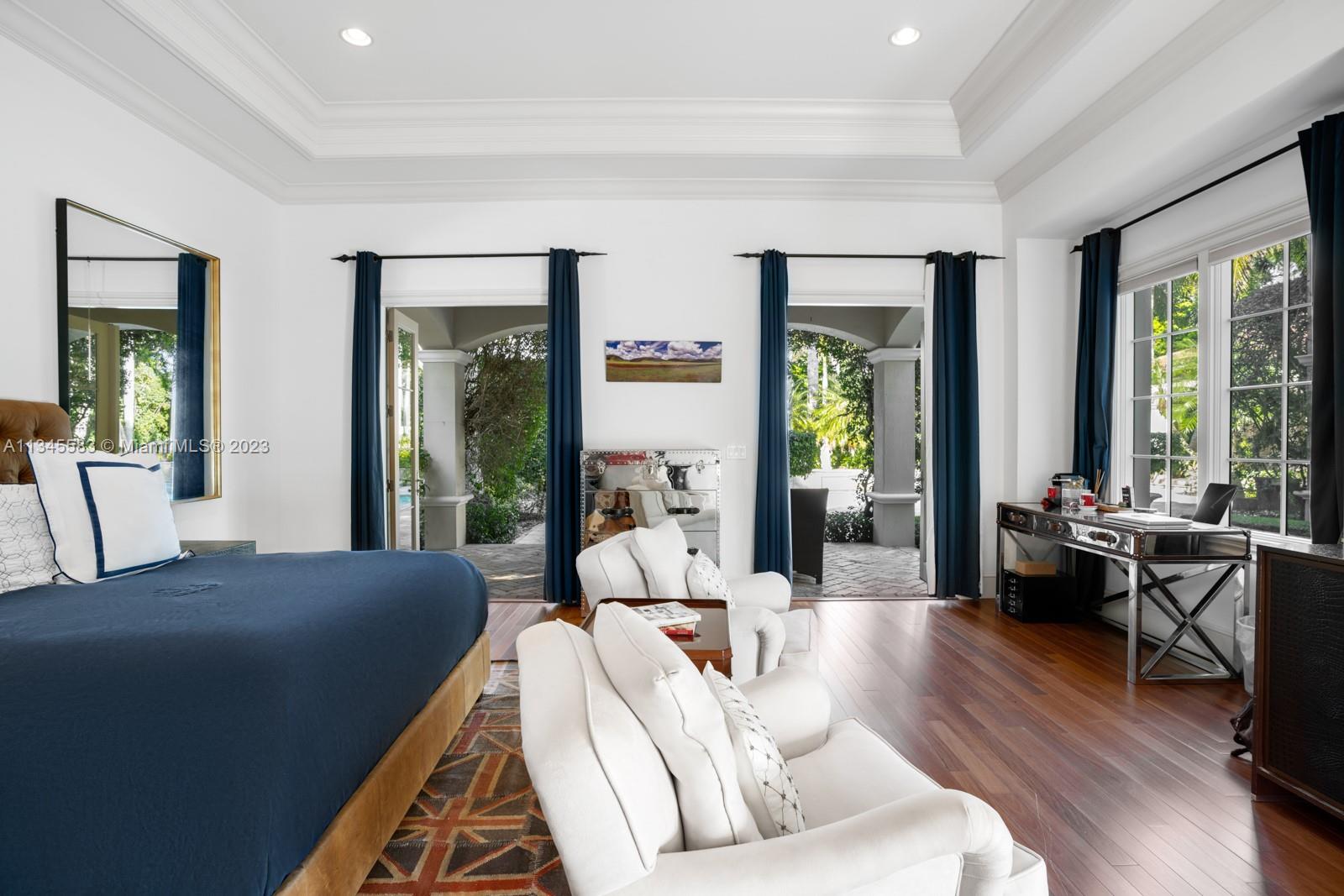 Bedroom with a navy bed, white armchairs, and glass doors opening to a garden patio.