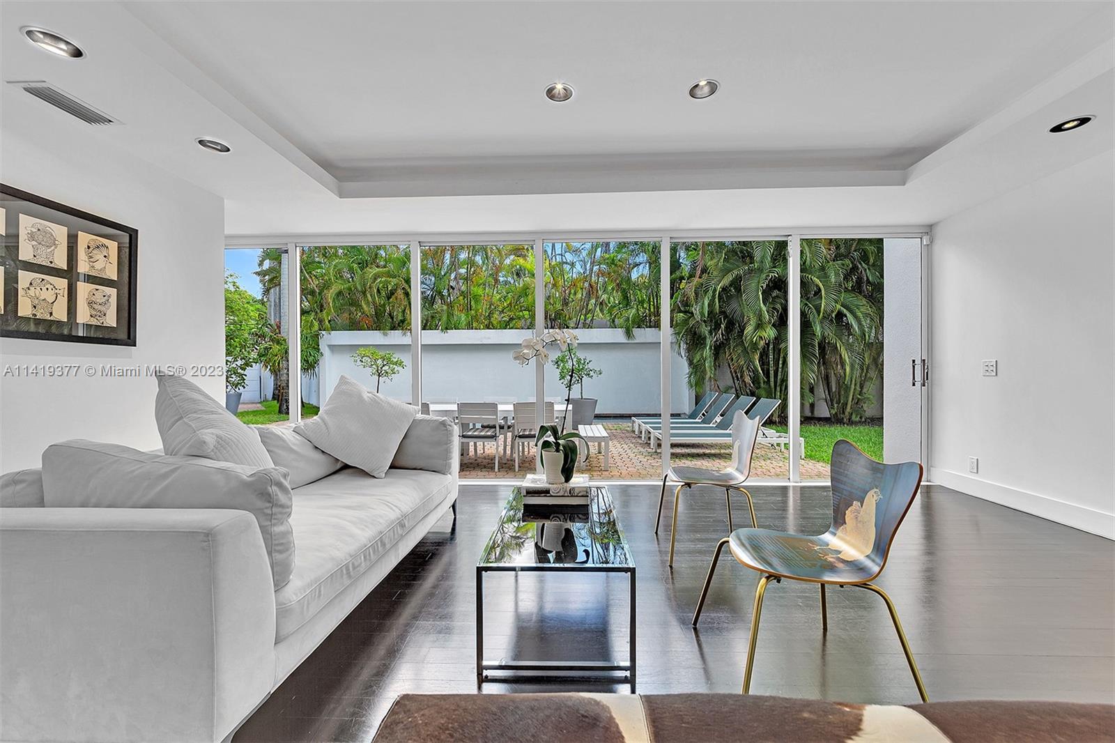 Living room with a white sofa and sliding glass doors opening to a garden patio.