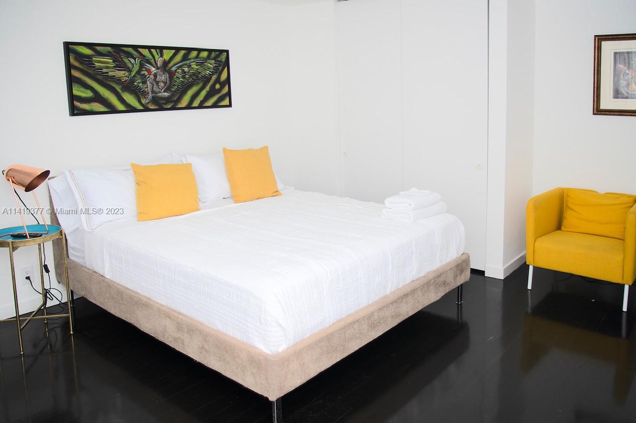 Bedroom with a white bed, yellow pillows, and a matching armchair.