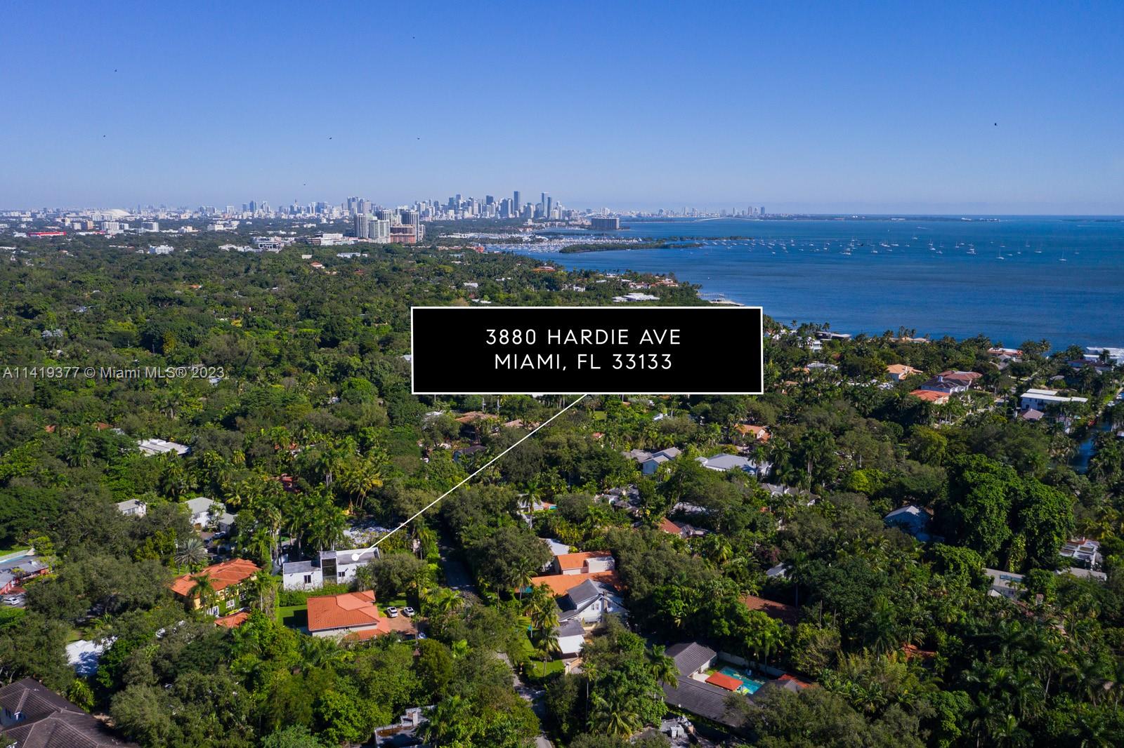 Aerial view of 3880 Hardie Ave amid leafy Miami homes, with bay and skyline.