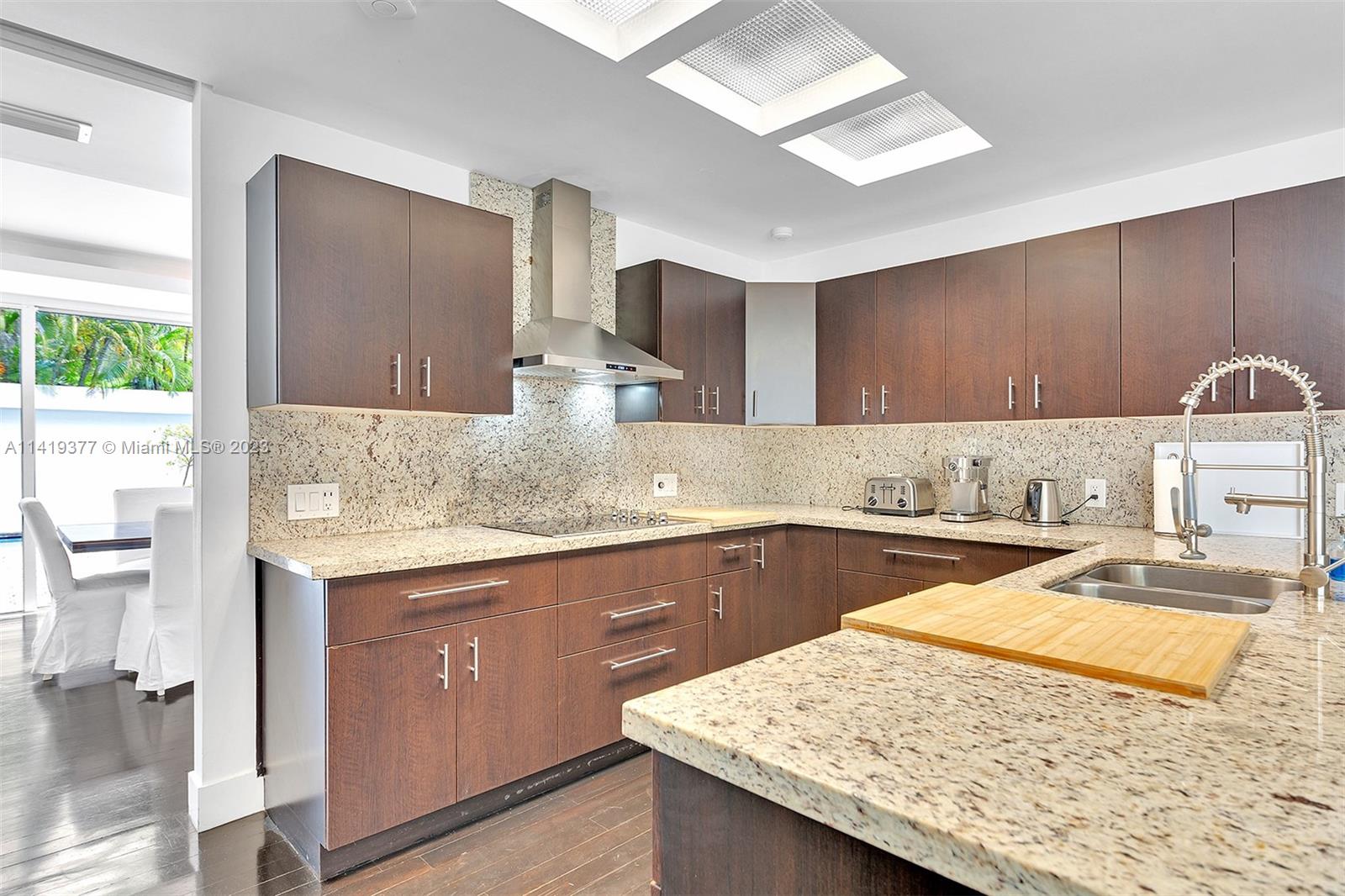 Modern kitchen with dark wood cabinets, speckled stone counters, and a large island.