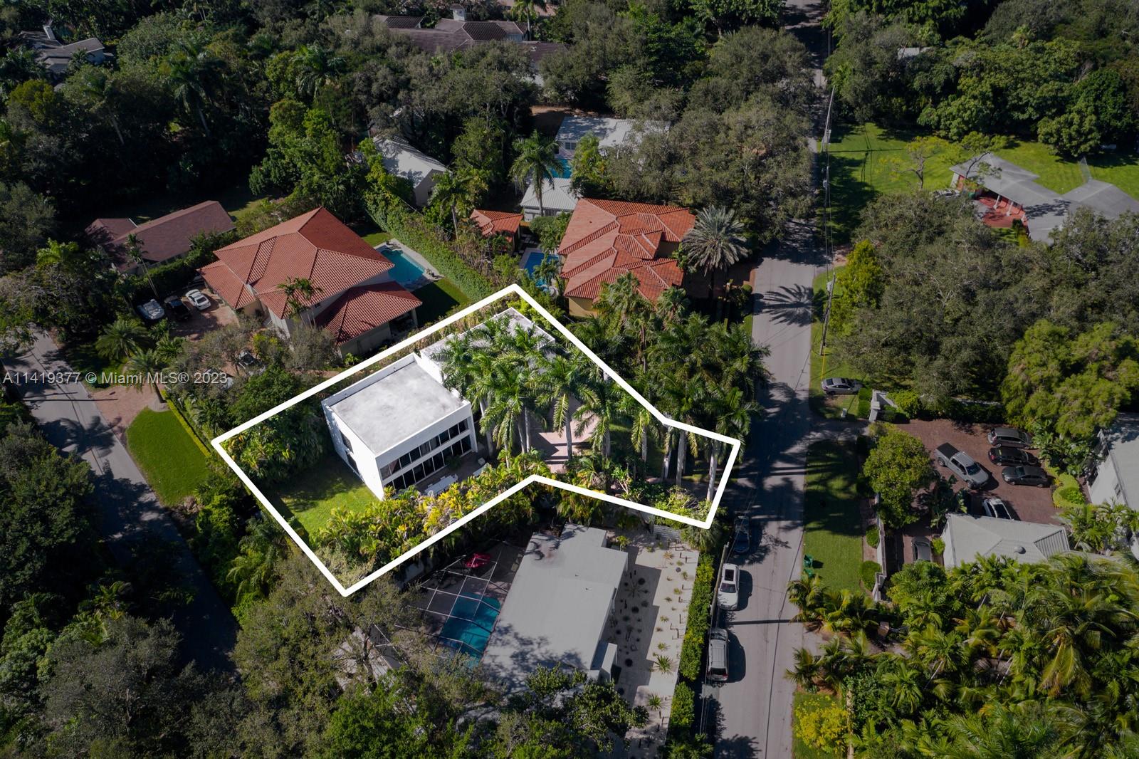 Aerial view of a modern home and palm-filled lot outlined in white.