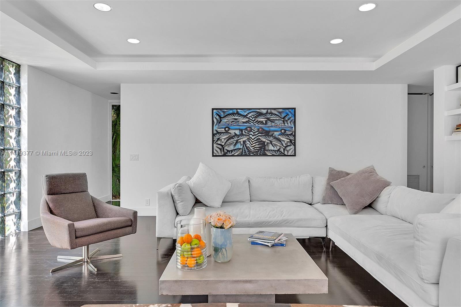 Modern living room with a white sectional, mauve swivel chair, and framed artwork.