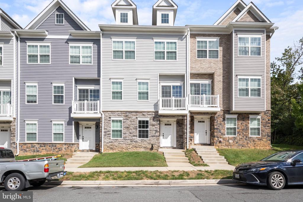 Attached townhouses with gray siding, stone accents, and white balconies along the front.