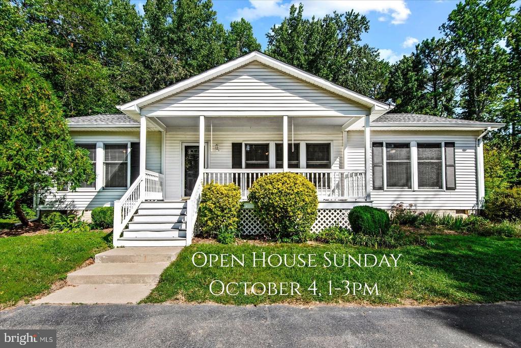 White single-story home with a covered porch, front steps, and an open house announcement.