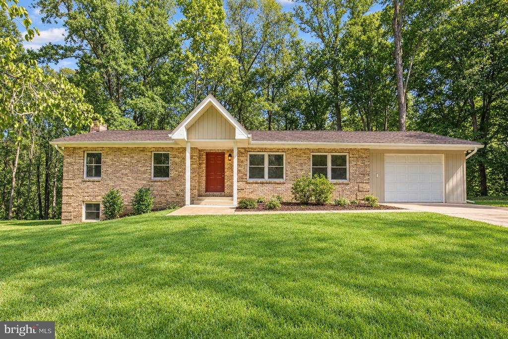Single-story brick house with a red front door, attached garage, and broad lawn.