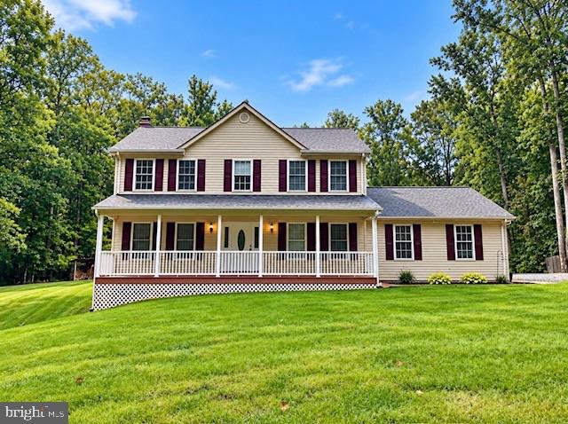 Two-story beige home with burgundy shutters, a long white porch, and a broad green lawn.