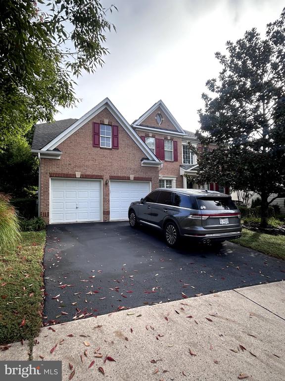 Brick two-story house with red shutters, double garage doors, and an SUV in the driveway.