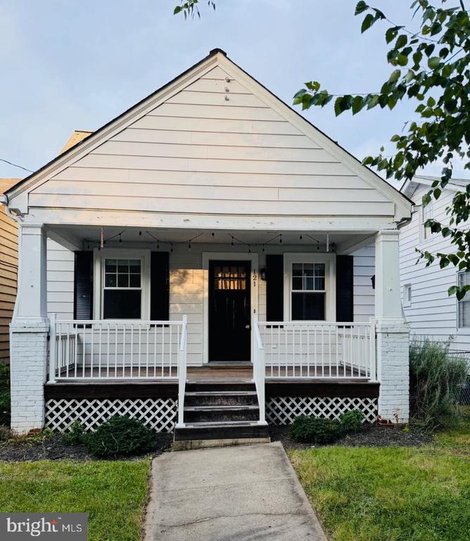 White gabled house with a covered porch, black shutters, and a walkway to the front steps.