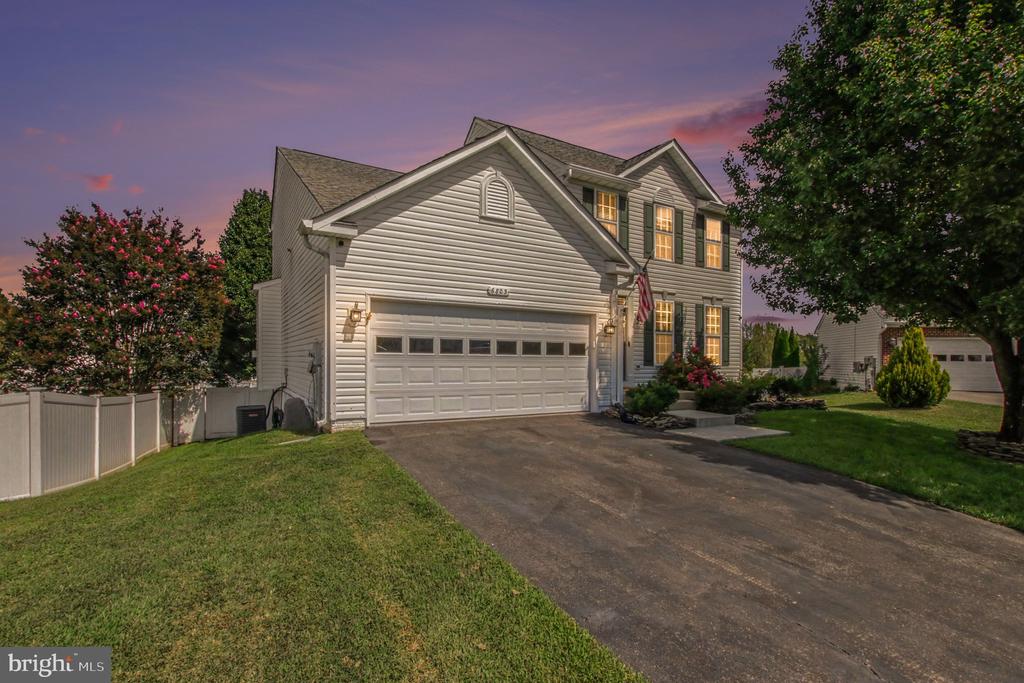 Two-story gray-sided home with a double garage and landscaped driveway at dusk.