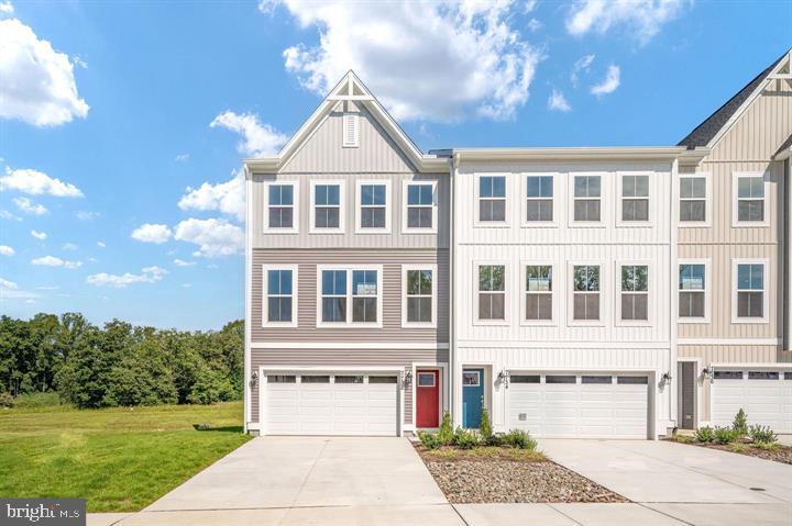 Three-story attached townhomes with pale siding, front-entry garages, and concrete driveways.