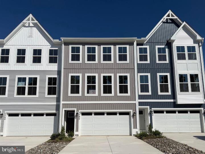 Row of attached townhomes with gray-and-white facades, peaked gables, and front garages.