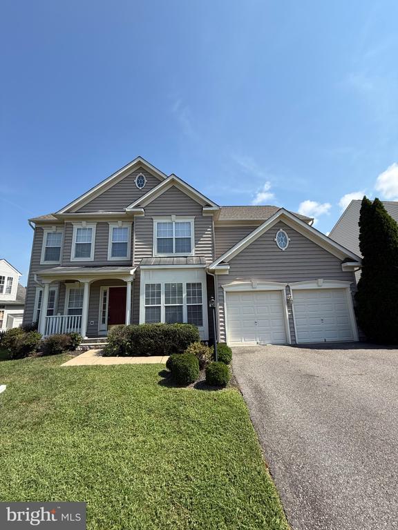 Two-story gray house with a covered porch, two-car garage, and landscaped front lawn.