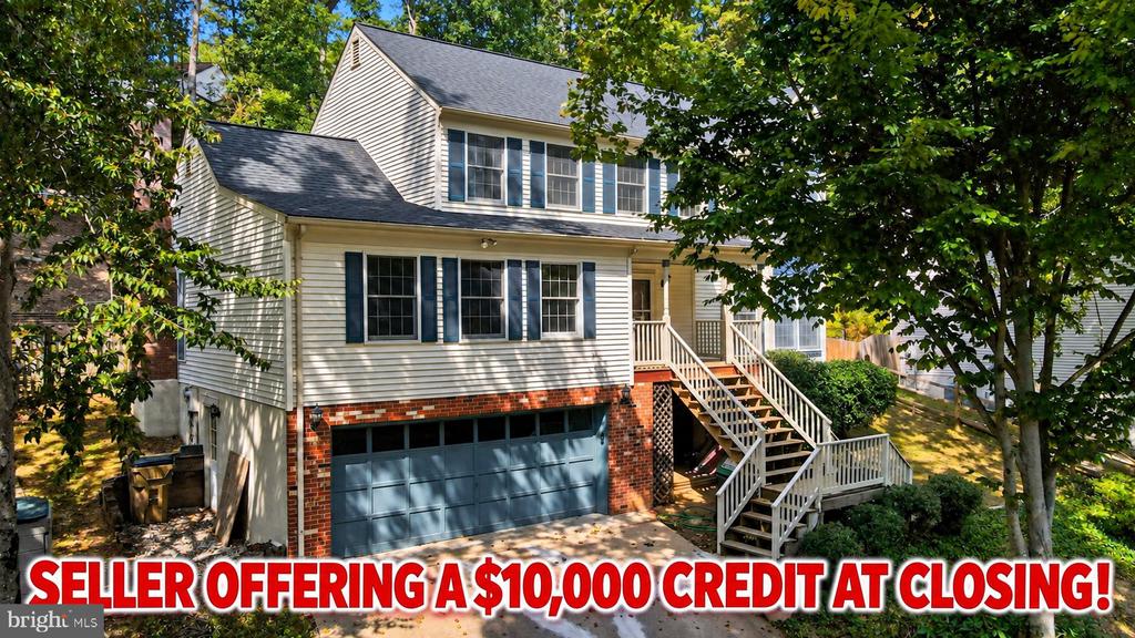 Two-story house with blue shutters, brick lower level, attached garage, and a long staircase to the entrance.