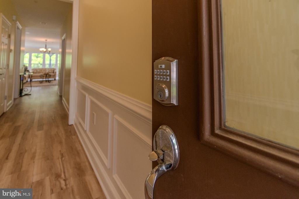 Entry hallway with keypad front-door lock, wood flooring, and a furnished living room beyond.