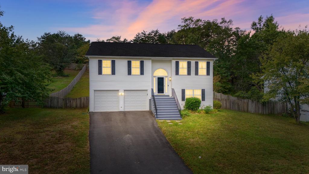 Two-story split-level house with a two-car garage and illuminated windows at dusk.